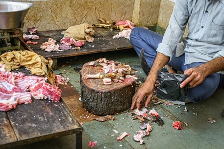 Meat shop worker chopping up goat or mutton in a mutton shop, Jodhpur, Rajasthan, India, 2022