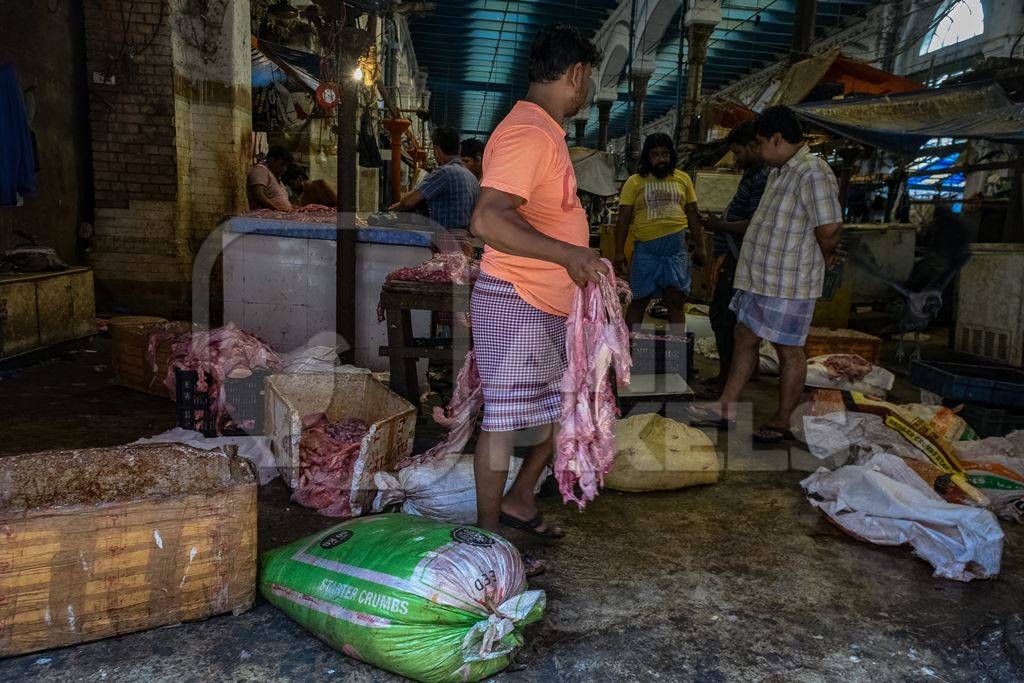Worker handling pieces of meat at the meat market inside New Market, Kolkata, Inida, 2022