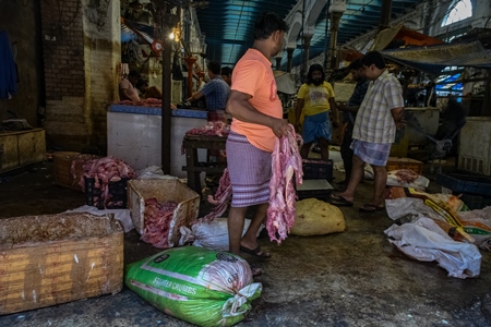 Worker handling pieces of meat at the meat market inside New Market, Kolkata, Inida, 2022