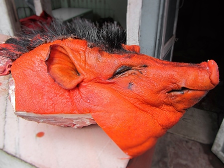 Orange dyed boar head on sale at a market in Nepal