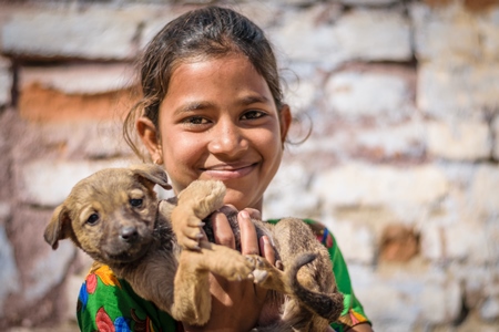 Girl holding small cute stray street puppy in urban city