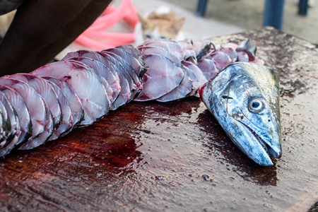 Indian seer fish cut up by seller at Malvan fish market on beach in Malvan, Maharashtra, India, 2022