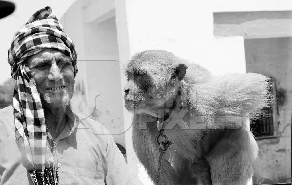 Man with monkey tied on a rope in black and white