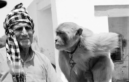 Man with monkey tied on a rope in black and white