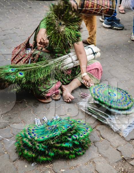 Women selling green peacock feather fans on sale in street