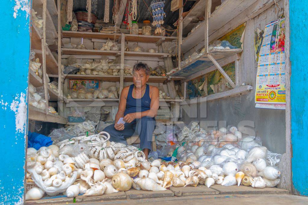 Indian man with shop selling many sea shells  in Guwahati in Assam in India