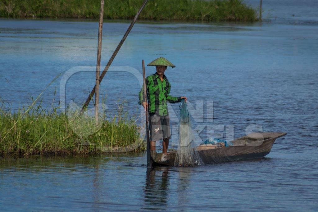 Fisherman fishing from a boat with a net on Loktak Lake