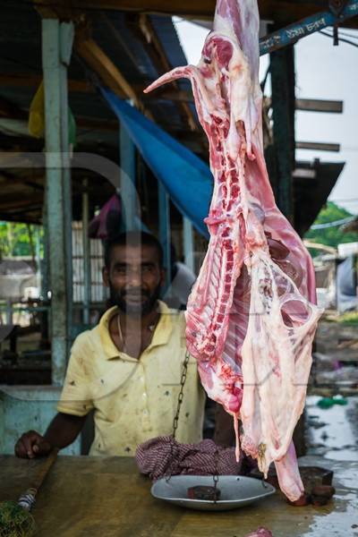 Goat meat hanging up at a mutton shop with butcher