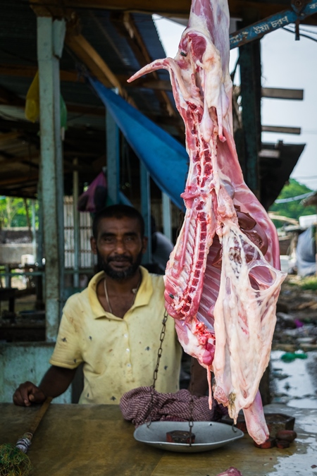 Goat meat hanging up at a mutton shop with butcher