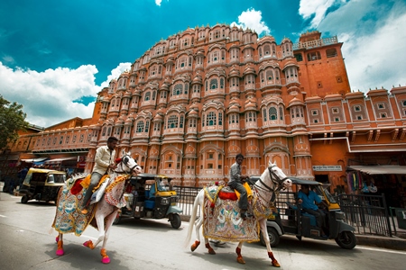 Two decorated horses with riders outside Hawa Mahal