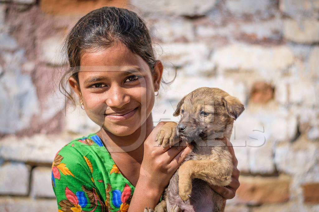 Girl holding small cute stray street puppy in urban city