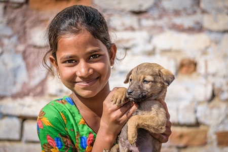 Girl holding small cute stray street puppy in urban city