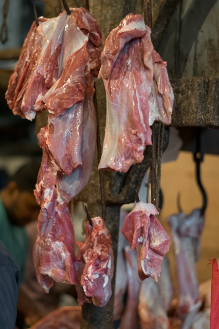 Pieces of meat hanging on hooks inside Crawford meat market in Mumbai, India