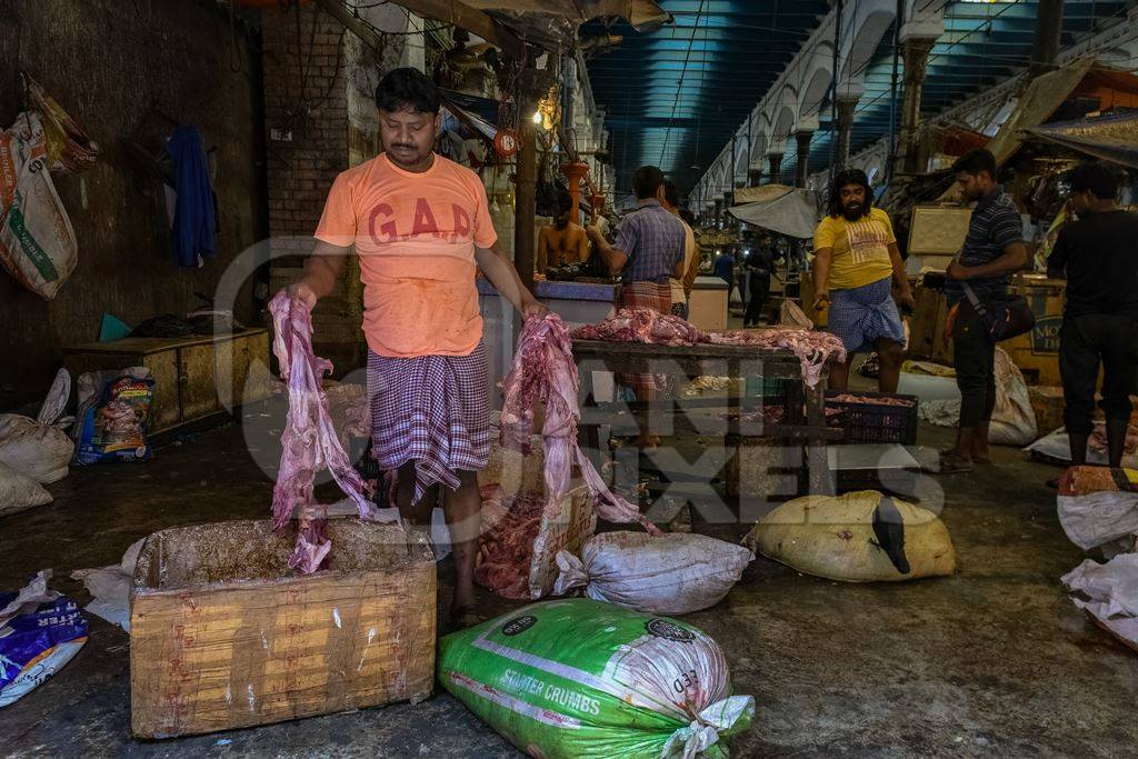 Worker handling pieces of meat at the meat market inside New Market, Kolkata, Inida, 2022