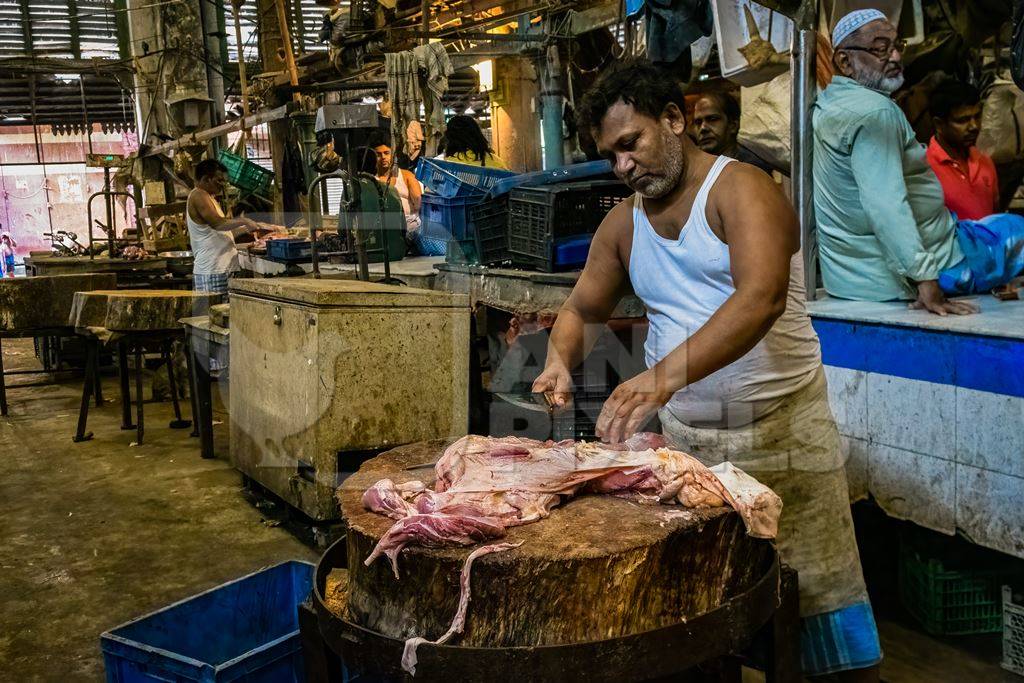 Buffalo meat being cut up by butchers at a meat market inside New Market, Kolkata, India, 2022