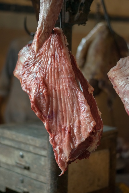 Piece of buffalo meat hanging on hooks inside Crawford meat market in Mumbai, India, 2016