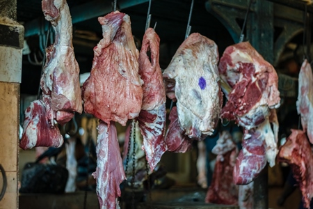 Pieces of buffalo meat hanging on hooks inside Crawford meat market in Mumbai, India, 2016