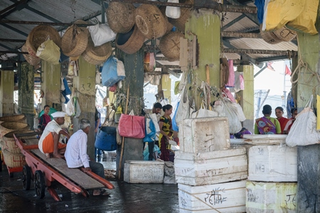 People at a fish market with boxes of fish on sale at a fish market at a fish market at Sassoon Docks