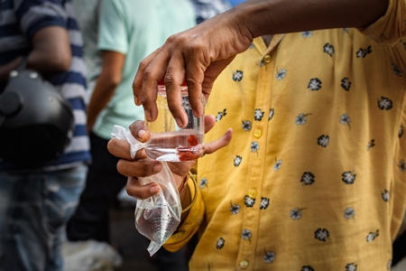 A buyer examines betta fish or siamese fighting fish in small containers on sale at Galiff Street pet market, Kolkata, India, 2022