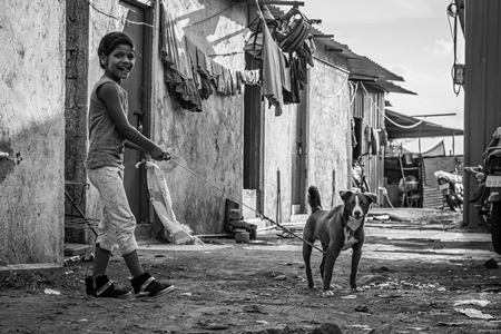 Girl with Indian pariah puppy dog kept as pet in urban city in black and white, Maharashtra, India, 2021