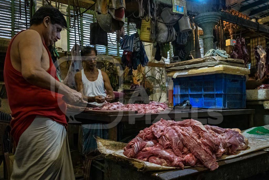 Buffalo meat being cut up by butchers at a meat market inside New Market, Kolkata, India, 2022