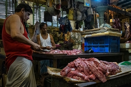 Buffalo meat being cut up by butchers at a meat market inside New Market, Kolkata, India, 2022