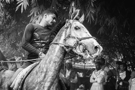 Horse in a horse race at Sonepur cattle fair with spectators watching in black and white