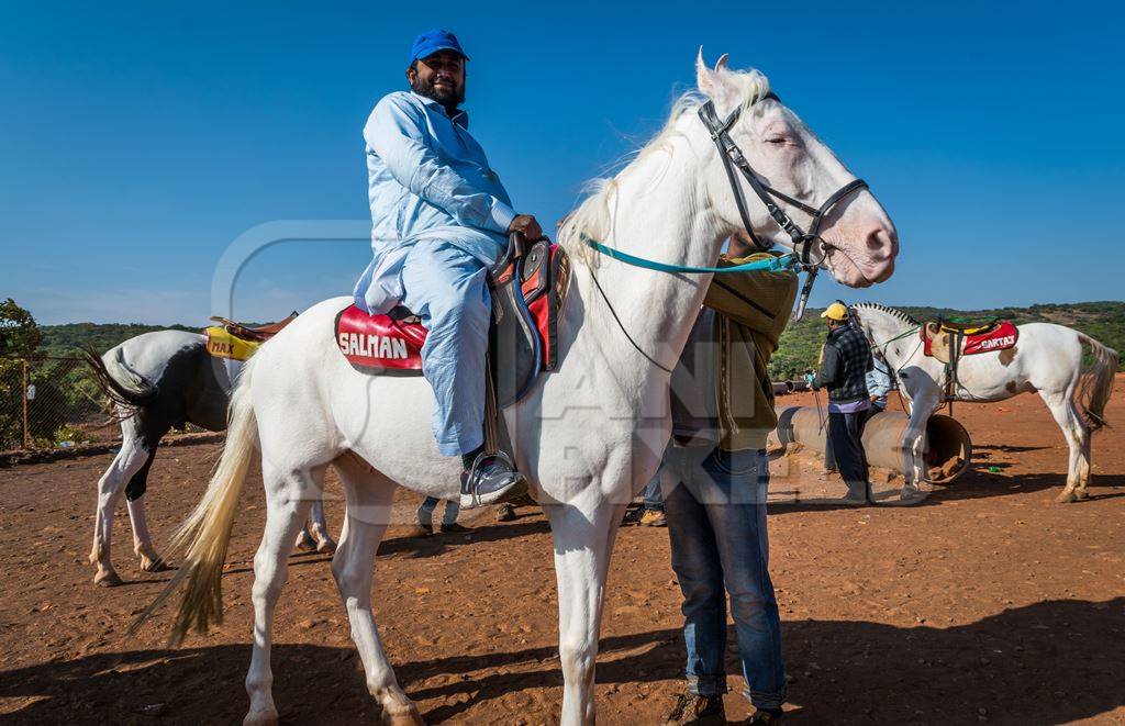 Man sitting on white horse used for tourist rides