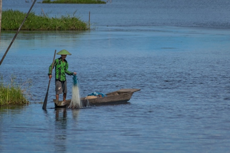 Fisherman fishing from a boat with a net on Loktak Lake