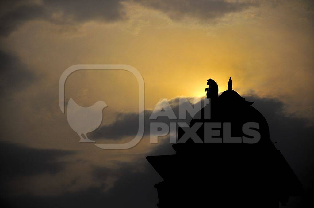 Silhouette of monkey sitting on top of temple at dawn or dusk