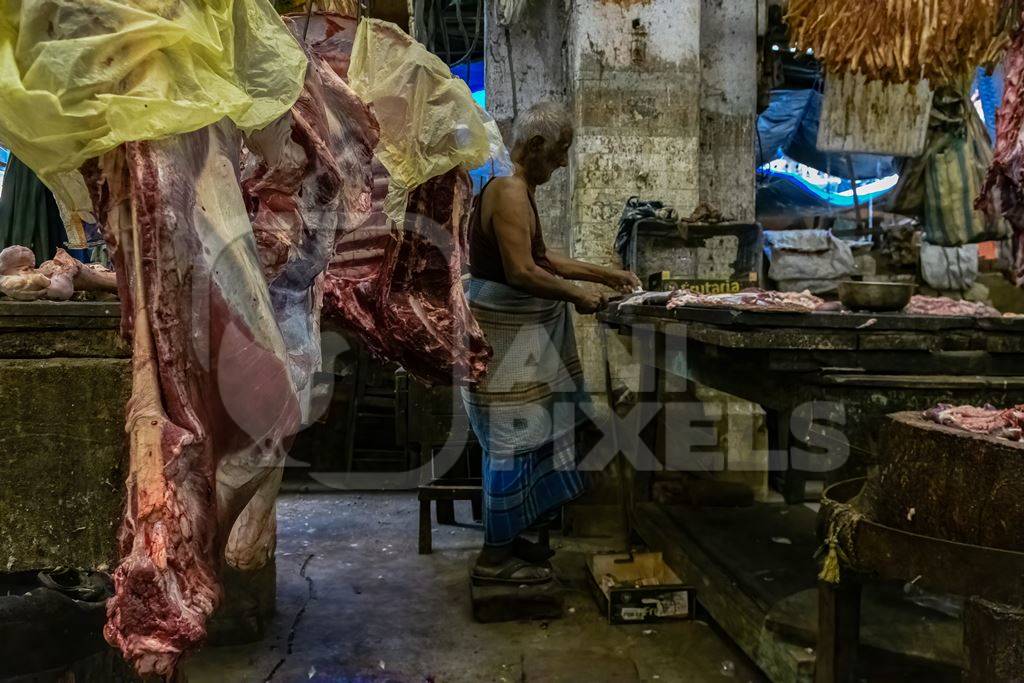 Buffalo meat being cut up by butchers at a meat market inside New Market, Kolkata, India, 2022