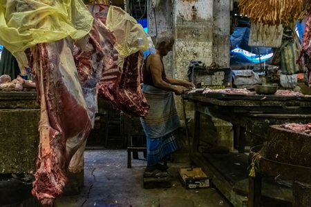 Buffalo meat being cut up by butchers at a meat market inside New Market, Kolkata, India, 2022