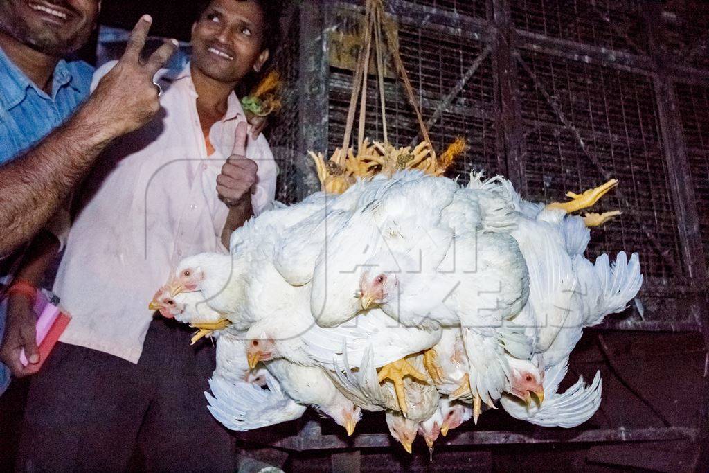 Broiler chickens hanging upside down being unloaded from transport trucks near Crawford meat market in Mumbai