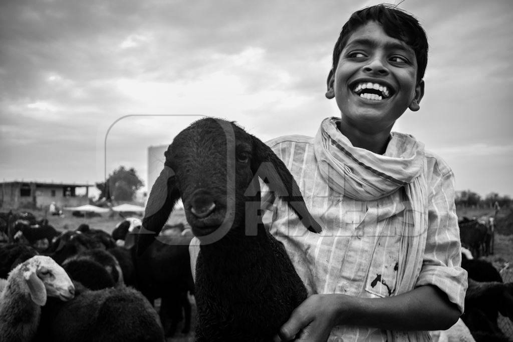 Boy smiling or laughing with goat in black and white