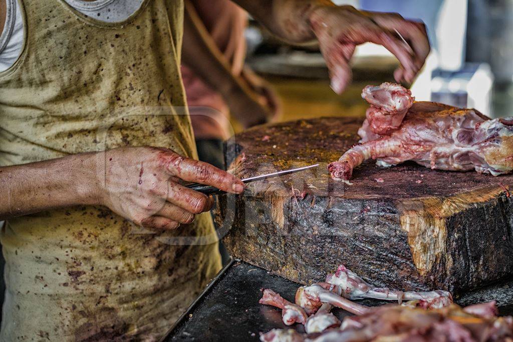 Butcher chopping up chicken at chicken shop at Crawford meat market