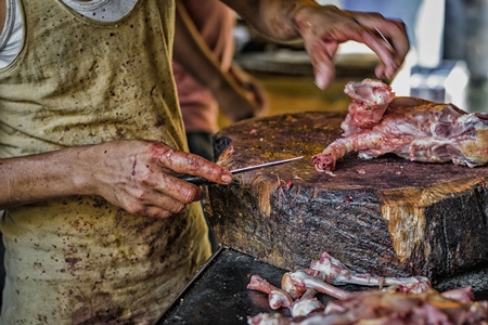 Butcher chopping up chicken at chicken shop at Crawford meat market