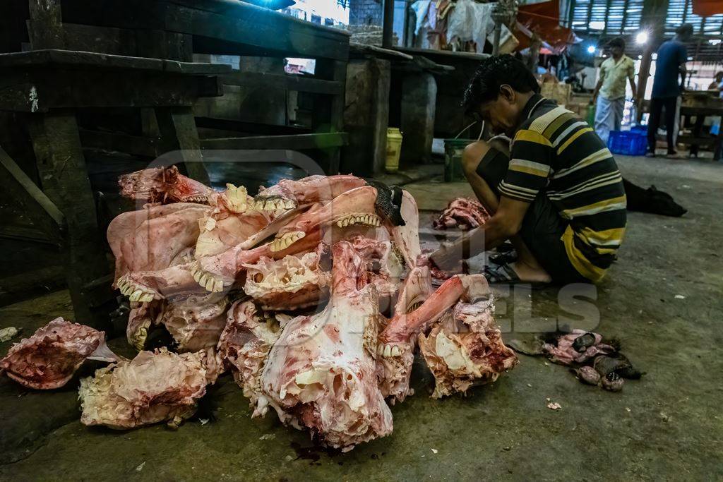 A pile of buffalo heads or skulls being cut up by butchers at a meat market inside New Market, Kolkata, India, 2022