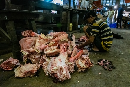 A pile of buffalo heads or skulls being cut up by butchers at a meat market inside New Market, Kolkata, India, 2022